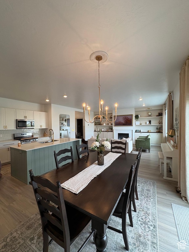 dining space with a notable chandelier, light wood-type flooring, and sink