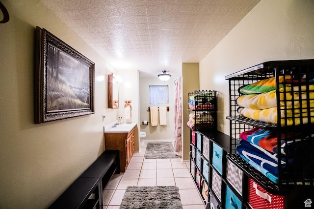 bathroom featuring vanity, toilet, tile patterned floors, and a textured ceiling