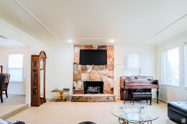carpeted living room featuring a stone fireplace, a healthy amount of sunlight, and ornamental molding