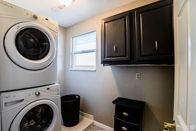 laundry room featuring cabinets and stacked washer and dryer