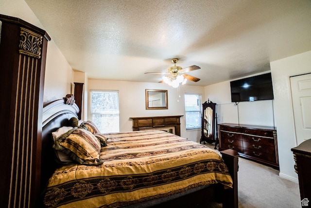 carpeted bedroom featuring ceiling fan and a textured ceiling