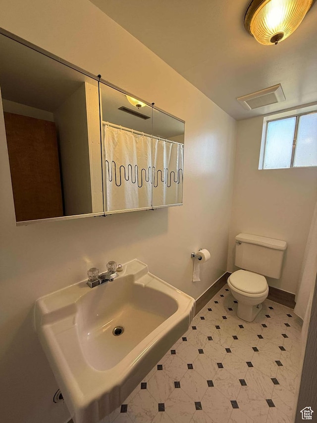 bathroom featuring baseboards, visible vents, toilet, and a sink