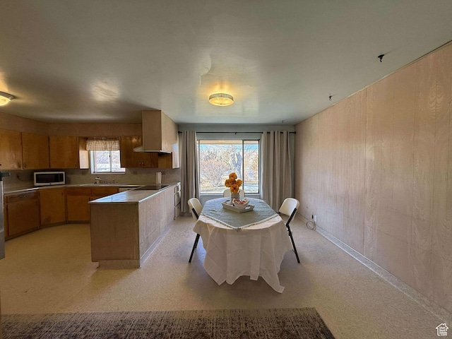 kitchen featuring a sink, black electric cooktop, stainless steel microwave, and a peninsula