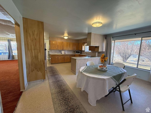 dining space with baseboards, light colored carpet, and a wealth of natural light