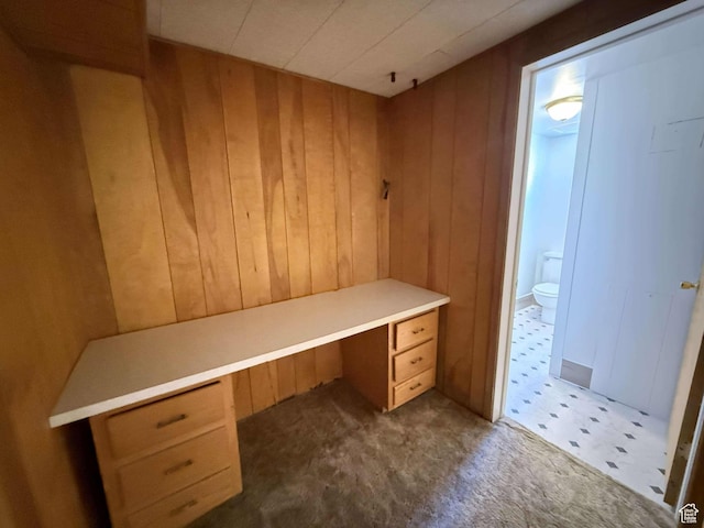 unfurnished office featuring built in desk and wooden walls