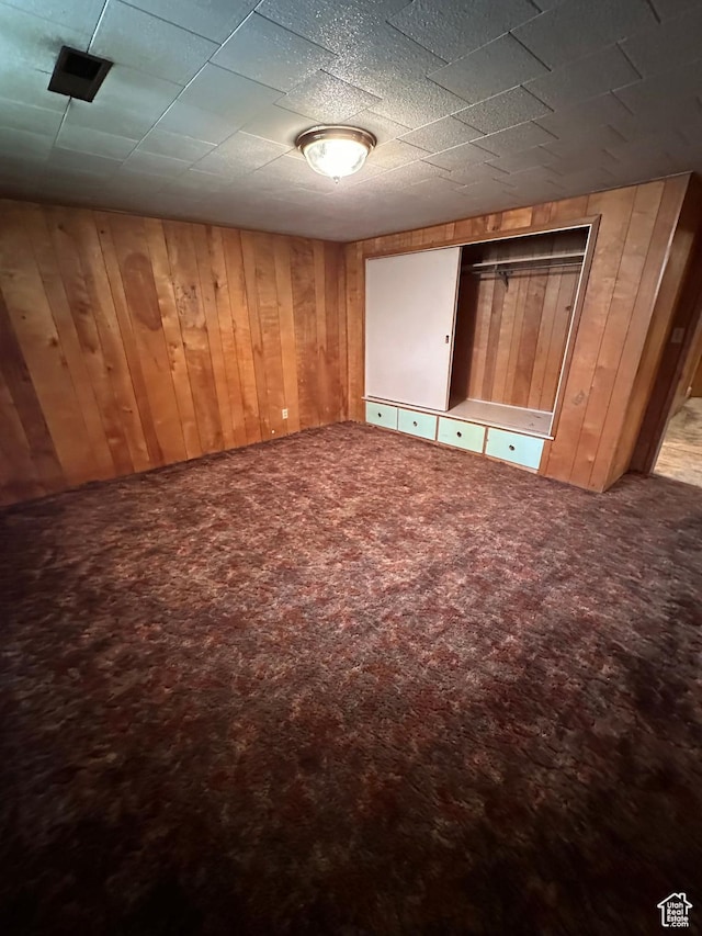 unfurnished bedroom featuring carpet floors and wood walls