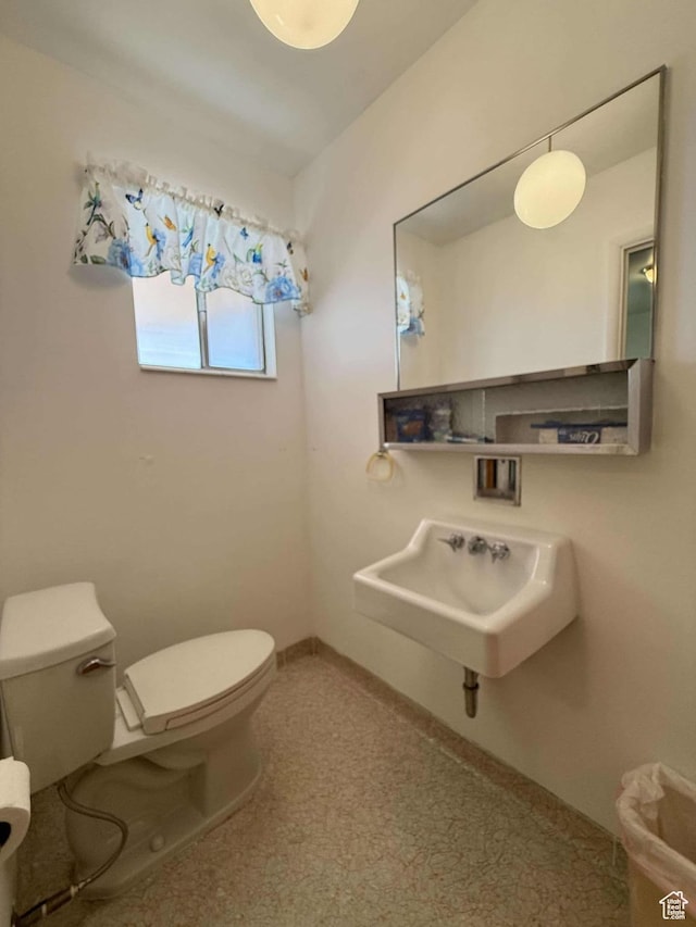 half bath with toilet, a sink, and baseboards