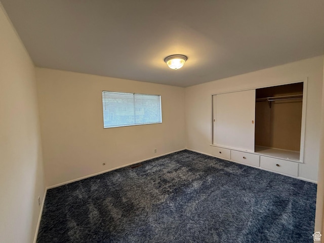 unfurnished bedroom with baseboards and dark carpet