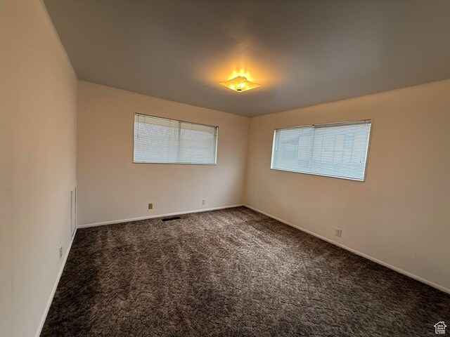 carpeted empty room featuring baseboards and visible vents