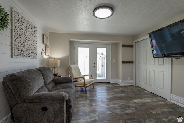 living room with a textured ceiling, dark wood-type flooring, and french doors