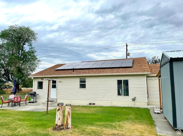 rear view of property featuring a lawn, a patio area, and solar panels
