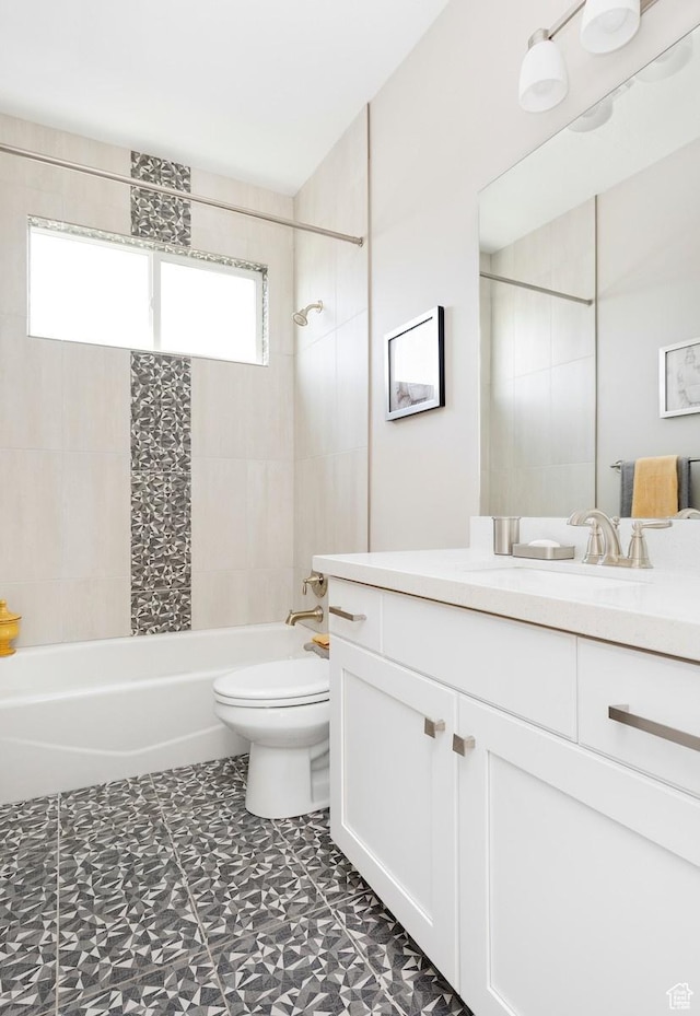 full bathroom with tiled shower / bath, vanity, and toilet