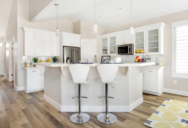 kitchen with tasteful backsplash, a kitchen island with sink, pendant lighting, and appliances with stainless steel finishes