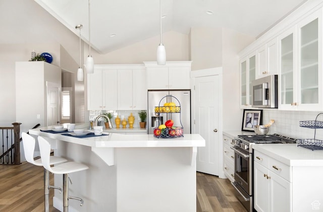 kitchen featuring white cabinetry, hanging light fixtures, tasteful backsplash, appliances with stainless steel finishes, and hardwood / wood-style flooring