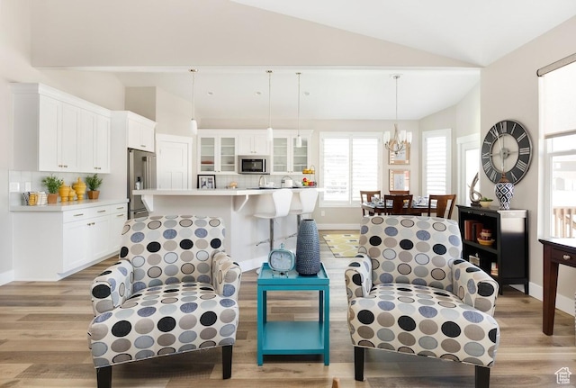 living room with vaulted ceiling, light hardwood / wood-style floors, and an inviting chandelier
