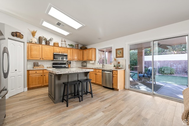 2461 W 1050 N, Hurricane, UT 84737 - kitchen with a center island, light hardwood / wood-style floors, appliances with stainless steel finishes, and tasteful backsplash