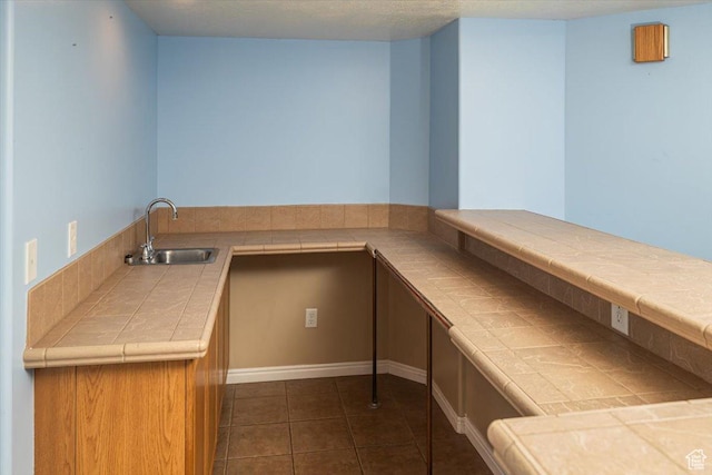 kitchen with tile countertops, sink, and dark tile patterned flooring