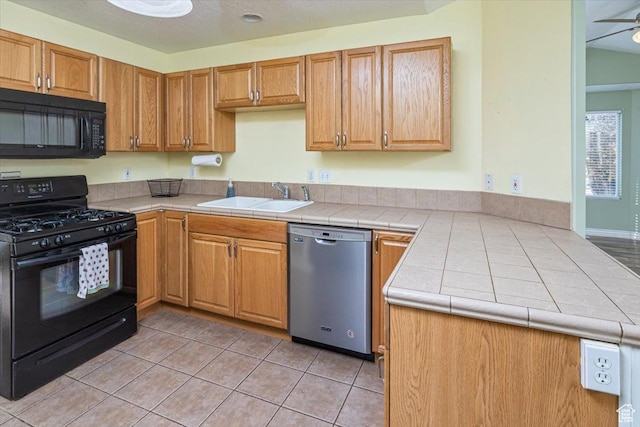 kitchen featuring black appliances, sink, ceiling fan, light tile patterned floors, and tile counters