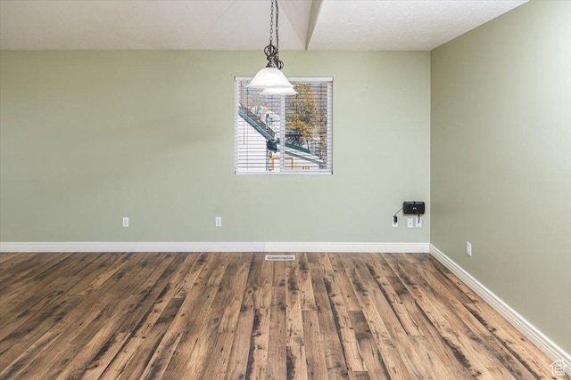 spare room featuring a textured ceiling and hardwood / wood-style flooring