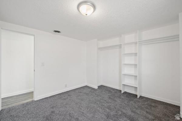 756 E 3rd St S, Ogden, UT 84404 - unfurnished bedroom featuring a closet, a textured ceiling, baseboards, and dark colored carpet