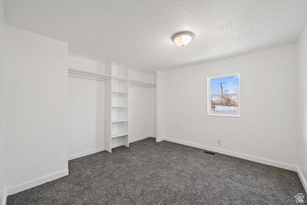 756 E 3rd St S, Ogden, UT 84404 - unfurnished bedroom with baseboards, a textured ceiling, a closet, and dark colored carpet