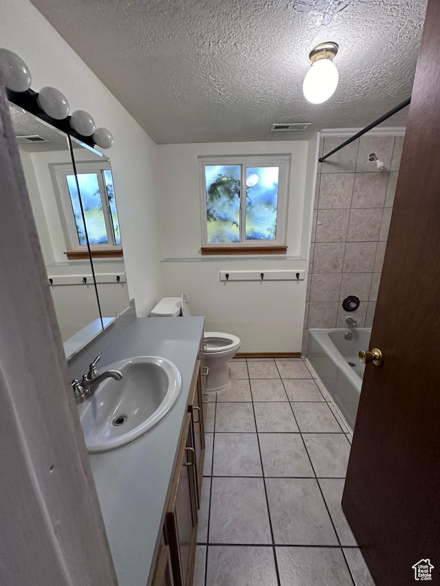 full bathroom with tile patterned floors, vanity, a textured ceiling, and tiled shower / bath