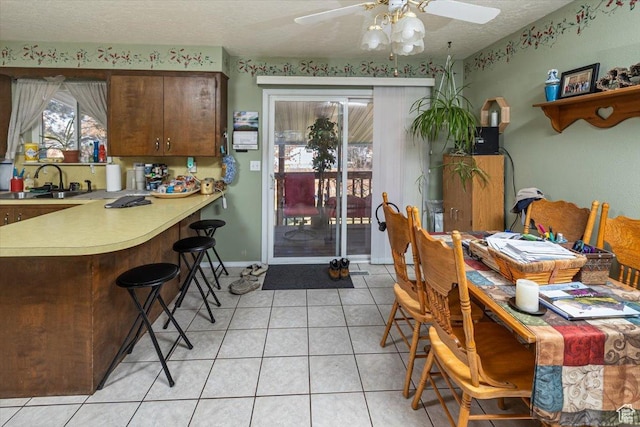 dining room featuring a textured ceiling, ceiling fan, light tile patterned floors, and sink