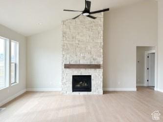 308 E Prestwick Ln, Stansbury Park, UT 84074 - unfurnished living room with a ceiling fan, a stone fireplace, wood finished floors, high vaulted ceiling, and baseboards