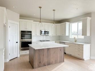 308 E Prestwick Ln, Stansbury Park, UT 84074 - kitchen with a center island, decorative light fixtures, light countertops, appliances with stainless steel finishes, and white cabinetry