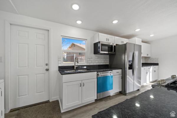 kitchen featuring white cabinets, appliances with stainless steel finishes, tasteful backsplash, and sink