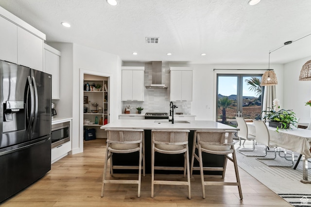 1823 W 180 N Street N, Hurricane, UT 84737 - kitchen featuring white cabinetry, wall chimney exhaust hood, decorative light fixtures, appliances with stainless steel finishes, and light wood-type flooring