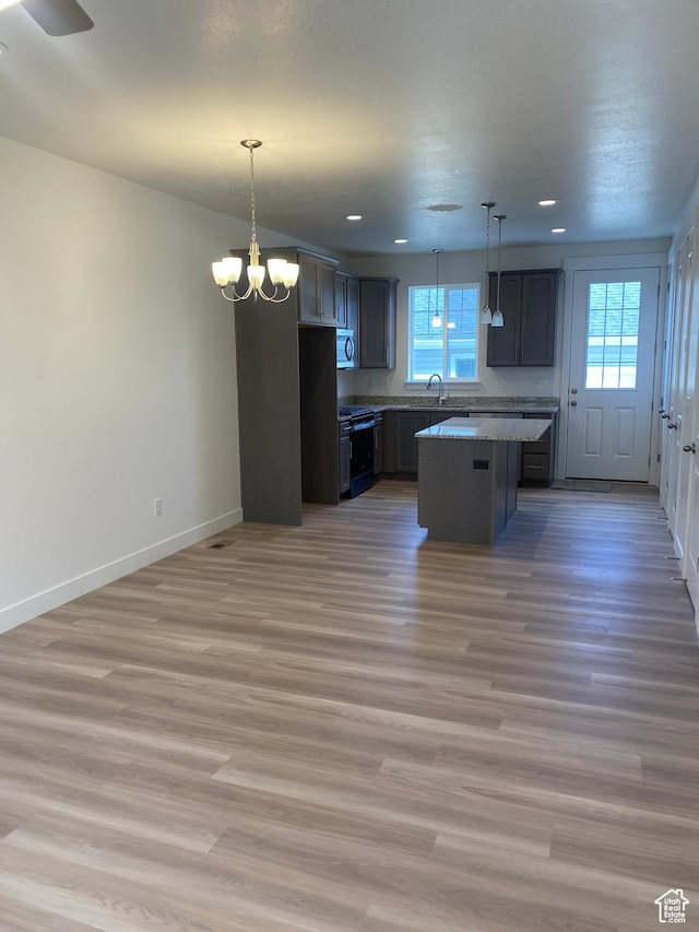 kitchen with decorative light fixtures, a kitchen island, and a healthy amount of sunlight
