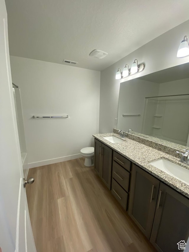 bathroom featuring vanity, toilet, wood-type flooring, and a shower