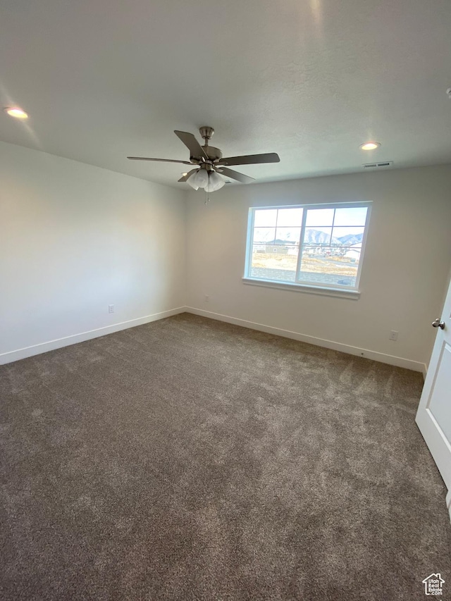 empty room with dark colored carpet and ceiling fan
