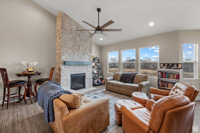 living room with ceiling fan, light wood-type flooring, a fireplace, and high vaulted ceiling