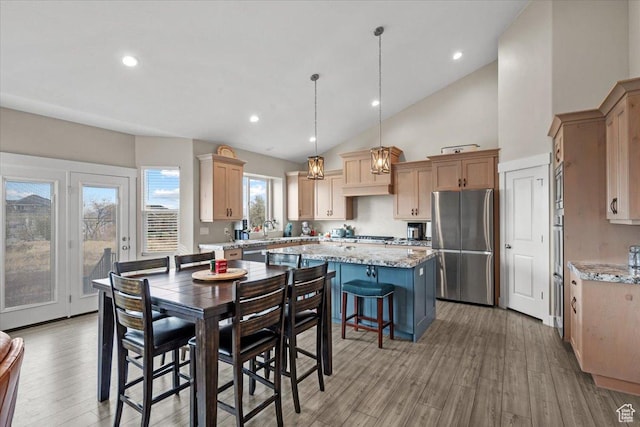 dining area with light wood-type flooring, sink, and high vaulted ceiling