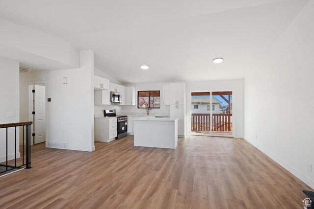 12875 S Aspen Cir, Riverton, UT 84065 - interior space featuring light wood-type flooring, stainless steel appliances, white cabinets, a kitchen island, and lofted ceiling