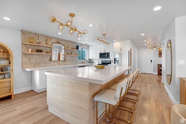 837 E 930 N, Pleasant Grove, UT 84062 - kitchen with white cabinets, a kitchen island, light wood-type flooring, and appliances with stainless steel finishes
