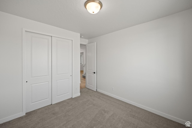 unfurnished bedroom featuring light carpet and a closet