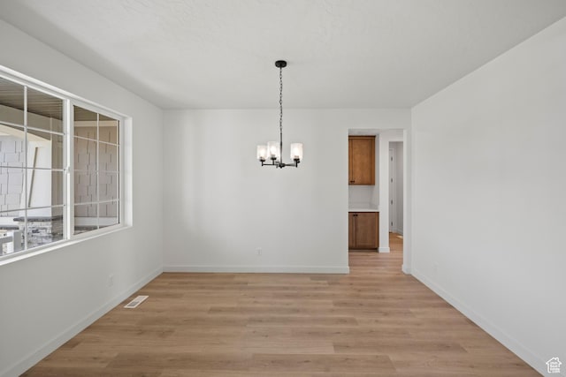 unfurnished dining area featuring light hardwood / wood-style floors and a chandelier