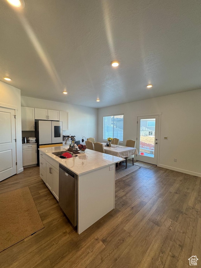 kitchen featuring stainless steel dishwasher, white cabinets, a center island with sink, and sink