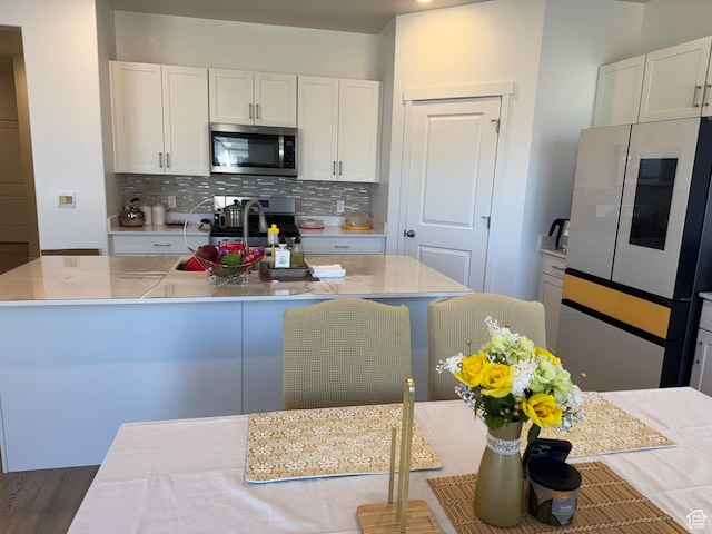 kitchen with decorative backsplash, white cabinetry, dark wood-type flooring, and appliances with stainless steel finishes