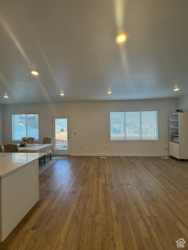 unfurnished living room with a textured ceiling and dark wood-type flooring