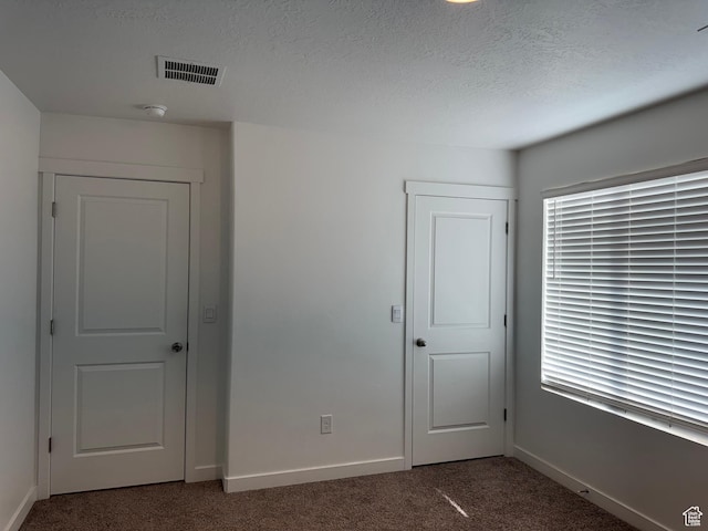 carpeted spare room with a textured ceiling