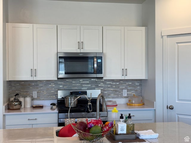 kitchen featuring decorative backsplash, white cabinetry, and appliances with stainless steel finishes