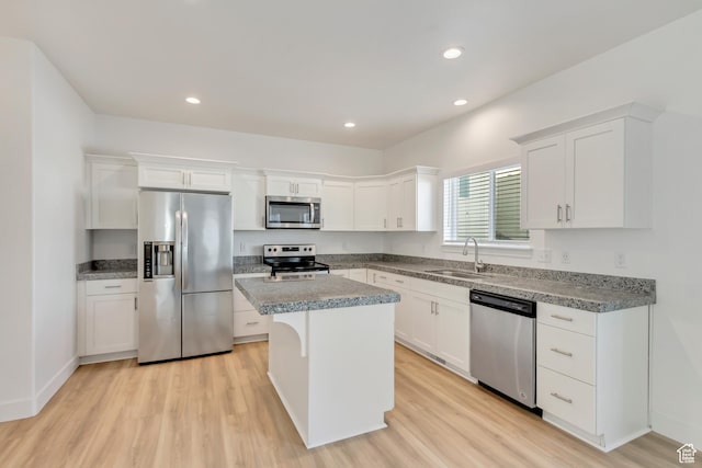 kitchen with white cabinets, sink, light wood-type flooring, appliances with stainless steel finishes, and a kitchen island