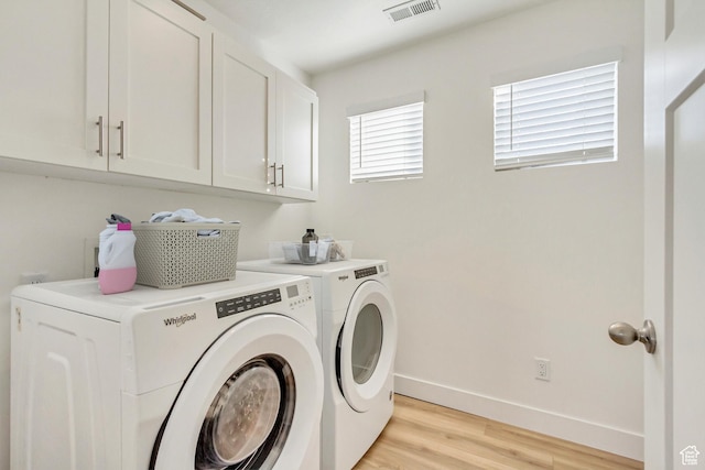 washroom with light hardwood / wood-style floors, cabinets, and washing machine and clothes dryer