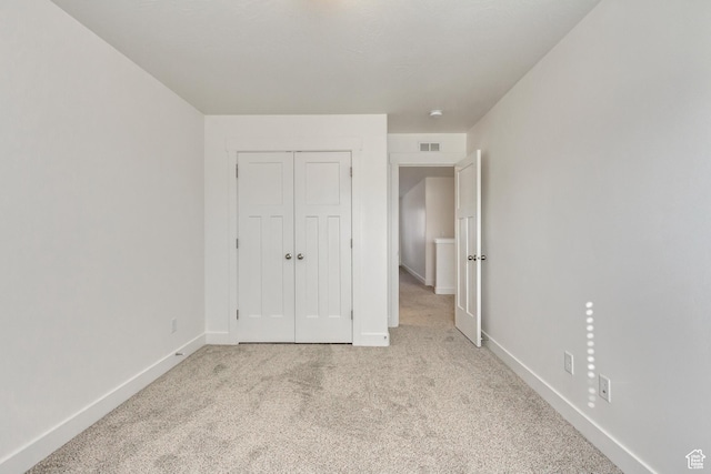 unfurnished bedroom with light colored carpet and a closet