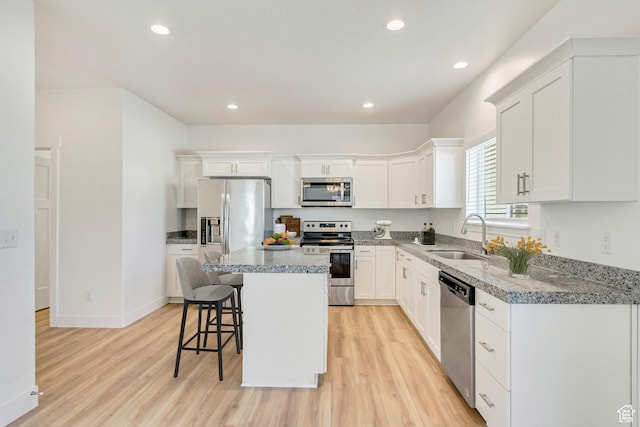 kitchen featuring sink, a kitchen island, stainless steel appliances, and light hardwood / wood-style flooring
