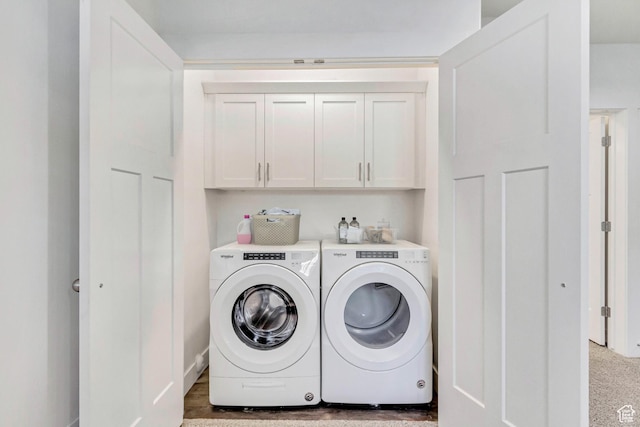 clothes washing area with separate washer and dryer and cabinets